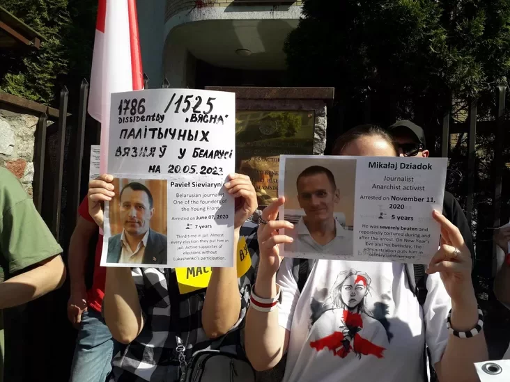 Участники акции солидарности в Белостоке осмотрительно прикрываются плакатами, чтобы не быть разоблаченными белорусскими спецслужбами