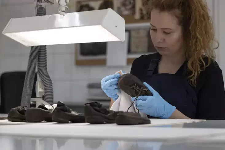 A worker rubs away dust on a shoe that belonged to a child victim of the death camp Auschwitz-Birkenau